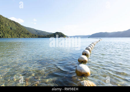 Blick auf den See Okataina und eine Linie von Bojen bei Sonnenuntergang in Neuseeland. Stockfoto