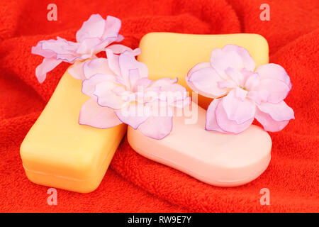 Bunte Seifen und Blumen auf rotem Tuch. Stockfoto