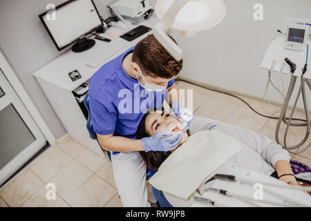 Frau, die Zähne bei man Zahnärzte in der zahnmedizinischen Klinik untersucht. Stockfoto