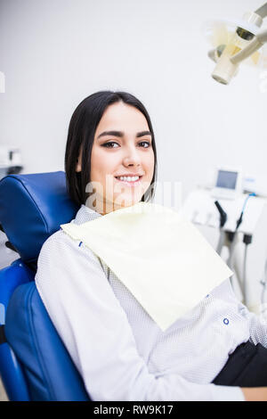 Junge weibliche Patienten Zahnarzt besuchen. Schön lächelnde Frau mit gesunden gerade weiße Zähne am Behandlungsstuhl sitzen. Zahnklinik. Stomatolo Stockfoto