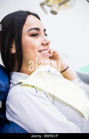 Junge weibliche Patienten Zahnarzt besuchen. Schön lächelnde Frau mit gesunden gerade weiße Zähne am Behandlungsstuhl sitzen. Zahnklinik. Stomatolo Stockfoto
