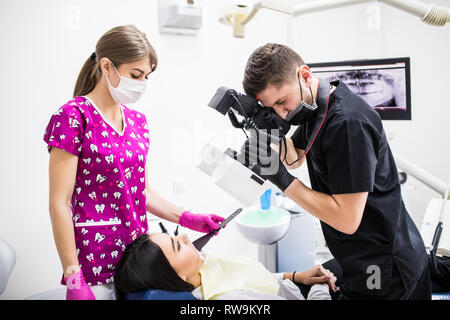 Der junge Mann, Zahnarzt, Mund, seine Arbeit auf die Zähne der weiblichen Patienten. Stockfoto