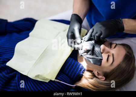 Eine latex-Platte, die den Zahn vom Rest der Mundhöhle während der Bestrahlung zu behandeln, zu isolieren. Bereiten Zahnärzte Zahn ein Meer zu installieren. Stockfoto