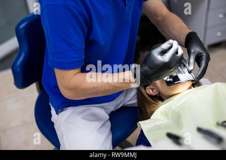 Mann an Zahnarzt Klinik erhält der zahnmedizinischen Behandlung ein Loch in einen Zahn zu füllen. Zahnersatz und Verbundmaterial Polymerisation Behandlung der Zähne. Stockfoto