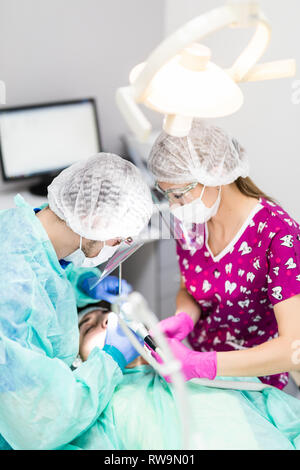 Arzt der Mann in den Schrank mit den Augen während des Verfahrens durch Zahnarzt und Assistent geschlossen. Stockfoto