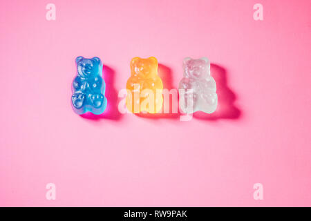 Eine Nahaufnahme von drei bunten Gummibärchen, auf einem rosa Hintergrund mit Mohn studio Licht fotografiert. Stockfoto
