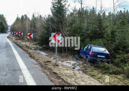 Ein Auto während der verkehrsunfall zerstört. Das Auto wird aufgegeben und steht von der Straße in den Bäumen. Stockfoto
