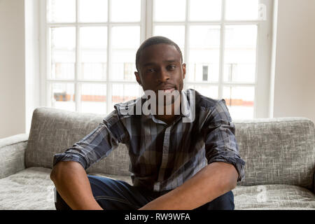 Afrikanische amerikanische Mann auf der Couch sitzen, Videokonferenz Stockfoto