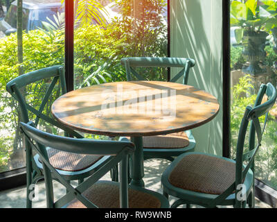 Vintage Holztisch und vier grünen Sessel in der Ecke Restaurant mit Fenster Glas in der Nähe des Garten. Stockfoto