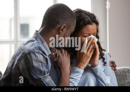 Pflege schwarzer Mann Hug unterstützt traurig weinenden Frau Stockfoto