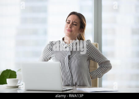 Müde müde Geschäftsfrau Arbeiter zurück reiben Gefühl unteren lumbalen Schmerzen Stockfoto