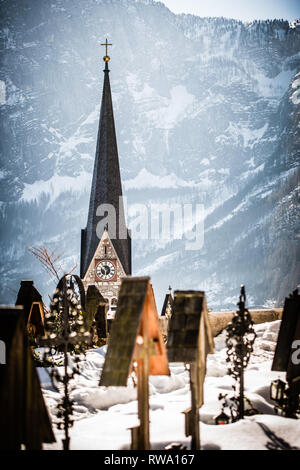 Der Turm der Evangelischen Kirche in Hallstatt mit schneebedeckten Berge in der Ferne Stockfoto