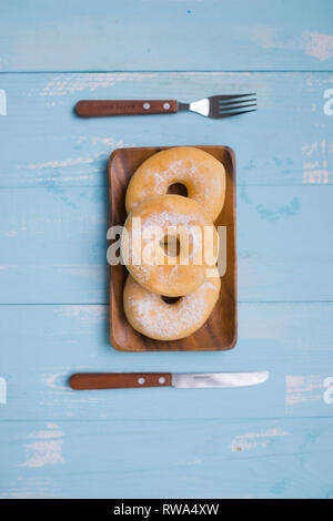 Frühstück Konzept: Donut auf Platte mit Messer und Gabel auf hölzernen Hintergrund Stockfoto