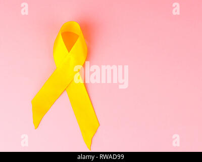 Childhood Cancer Awareness Gelbe Band auf rosa Hintergrund. Krebs im Kindesalter. Stockfoto