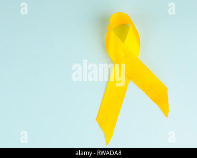 Childhood Cancer Awareness Ribbon Gelb auf blauem Hintergrund. Krebs im Kindesalter. Stockfoto