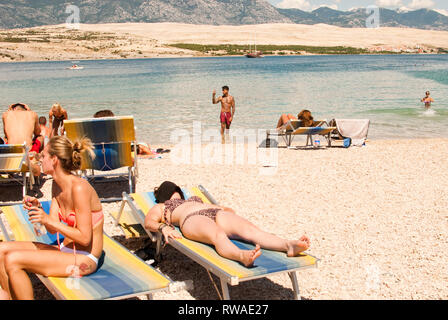 Junge Mann in Shorts und unter ständigen selfie im Meer am Strand Zrce, mit Sonnenbaden Frau im Vordergrund. Kroatien während Versteck Festival Stockfoto