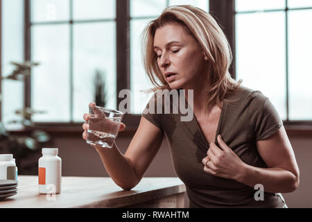 Blonde Frau, die unter Depressionen leiden Trinkwasser Stockfoto