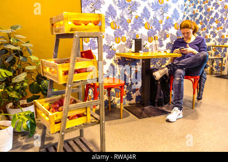Eine junge Frau in einer Bar, die auf ihre Abreise wartet, am Flughafen Wien, Österreich Generation Z Stockfoto