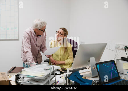 Reife Frau mit einem ernsten Gespräch mit einem älteren Kollegen im Büro. Stockfoto