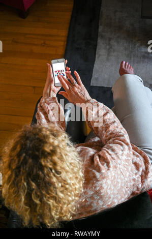 Reife Frau mit einem Apple iPhone im Internet zu Lesen und Senden von Nachrichten Schuß von oben nach unten Schauen. Stockfoto