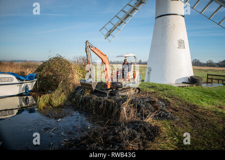 Workman, mit einem Bagger und Schaufel Fluss Thurne, auf der Norfolk​ Broads, Großbritannien zu Bagger Stockfoto