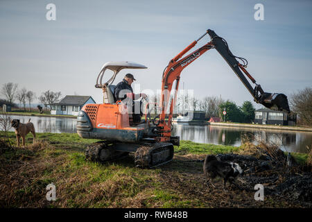 Workman, mit einem Bagger und Schaufel Fluss Thurne, auf der Norfolk​ Broads, Großbritannien zu Bagger Stockfoto