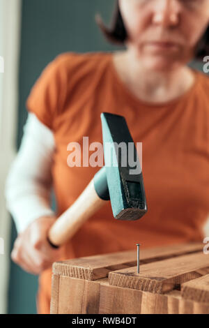 Frau Carpenter Nagel hämmern in Holzkiste in kleinen Unternehmen Holzarbeiten Workshop, selektiver Fokus Stockfoto