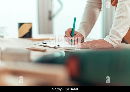 Selbständige Frau Carpenter Schreiben Hinweise zur Zwischenablage notepad Papier in kleinen Unternehmen Holzarbeiten workshop Stockfoto