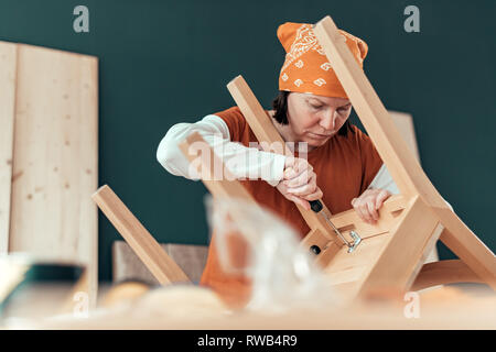 Frau Carpenter Reparatur Holz Stuhl Sitz in Small Business Holzarbeiten workshop Stockfoto