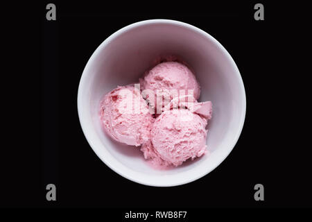 Drei Kugeln rosa Erdbeereis Schüssel in Weiß auf schwarzem Hintergrund Stockfoto