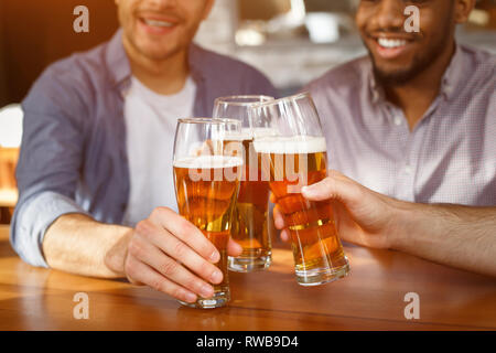 Beste Freunde klirren Biergläser in bar, Nahaufnahme Stockfoto