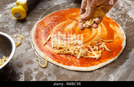 Mann hinzufügen Käse Pizza in der Küche Stockfoto