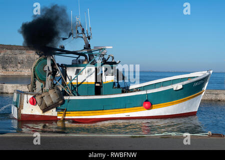 Frankreich, Oléron, 2018. Schwarz Dieseldämpfe Auspuffanlage, erzeugt von einem kleinen Fischerboot als der Kapitän bereitet die Trawler im Hafen von Château zu verlassen Stockfoto