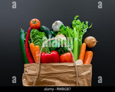 Frisches Bio-Gemüse in der braunen Papiertüte gegen dunkle Tabelle Hintergrund Stockfoto