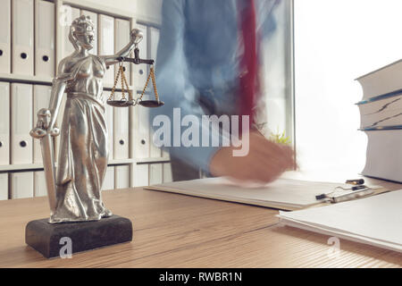 Rechtsanwalt Buch lesen und schreiben Notizen in Law Office, selektiver Fokus auf Statue der Muttergottes Gerechtigkeit, Langzeitbelichtung motion blur Effekt Stockfoto