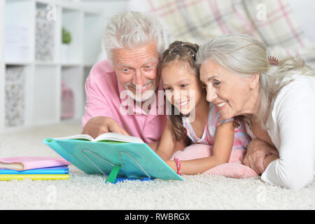 Portrait von großeltern Buch lesen mit Enkelin Stockfoto