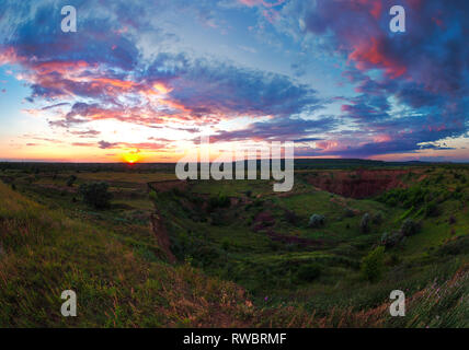 Helle Sommer bewölkter Sonnenuntergang über das grüne Tal. Abends outdoor. schöne Fotografie. Ukraine, Kriviy Rih. Ländliche weite Landschaft Stockfoto