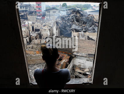 Quezon City, Philippinen. 6 Mär, 2019. Ein Bewohner betrachtet die verkohlten Wohnungen nach einem Brand in einem Wohngebiet in Quezon City, Philippinen, 6. März 2019. Rund 150 Häuser wurden in das Feuer dem Erdboden gleichgemacht, und 450 Familien obdachlos. Credit: rouelle Umali/Xinhua/Alamy leben Nachrichten Stockfoto