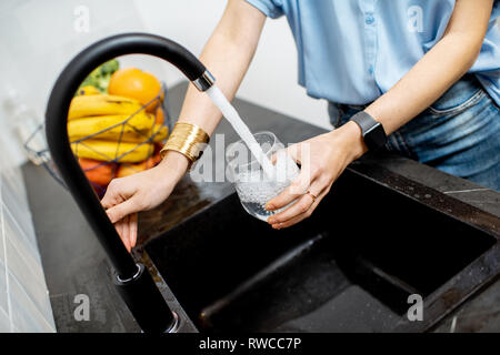 Frau Füllung Glas mit Leitungswasser zum Trinken auf der Küche Stockfoto
