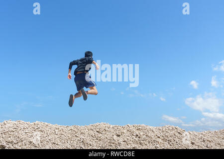 Junger Mann gegen den blauen Himmel Landschaft springen. Weiche Bild mit dem jungen Mann ist in Bewegung, wo einige verschwommen Effekt auf seinem Bein Bewegung zu zeigen. Stockfoto