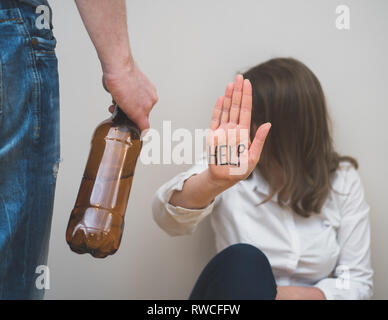 Home Gewalt Konzept. Verängstigte Frau und Mann Hand, die eine Flasche Wein. Stockfoto