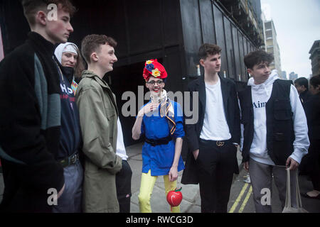 LONDON - 15. FEBRUAR 2019: Stilvolle Teilnehmer sammeln außerhalb 180 Strang für London Fashion Week. Mann in gelb Hose, blaue Jacke und einer Tüte Stockfoto