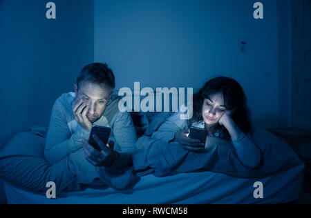 Life style Porträt der jungen gebohrt Paar nachts im Bett auf Smartphones mit Spielen, Social Media besessen, Apps gegenseitig ignorieren. Beziehung co Stockfoto