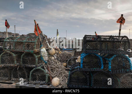 Ein Boot vertäut Gegen die Wharf ist sichtbar durch den Stapel der Reusen, Seile und Marker Bojen am Kai in Gourdon Hafen Stockfoto