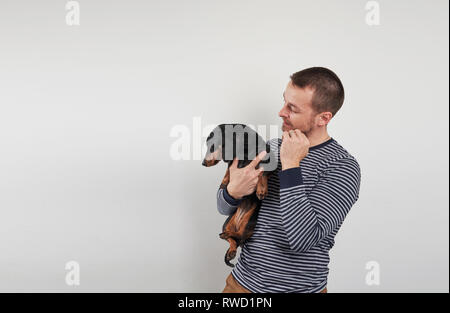 Mann hält ein Dackel in seinen Händen Stockfoto