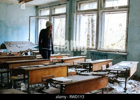 Frau geht durch einen Klassenraum, der vor langer Zeit in Folge der Reaktorkatastrophe von Tschernobyl wurde aufgegeben Stockfoto