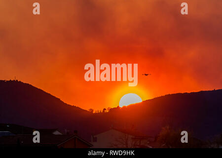 Canadair propeller Flugzeug fliegt über eine Stadt gegen einen schönen Sonnenuntergang Stockfoto