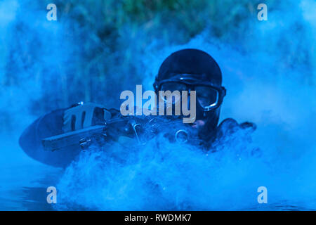 Frogman mit kompletter Tauchausrüstung und Waffen im Wasser. Stockfoto