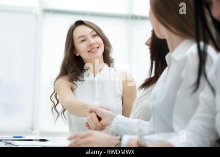 Freundliche Unternehmerin und client Handshaking, Sitzen am Tisch Stockfoto