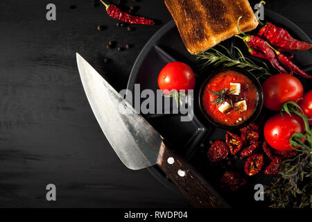 Tomatensuppe mit Chili und Gemüse. Gesundes Essen. Auf einem schwarzen Holz- Hintergrund. Ansicht von oben. Kopieren Sie Platz für Ihren Text. Stockfoto